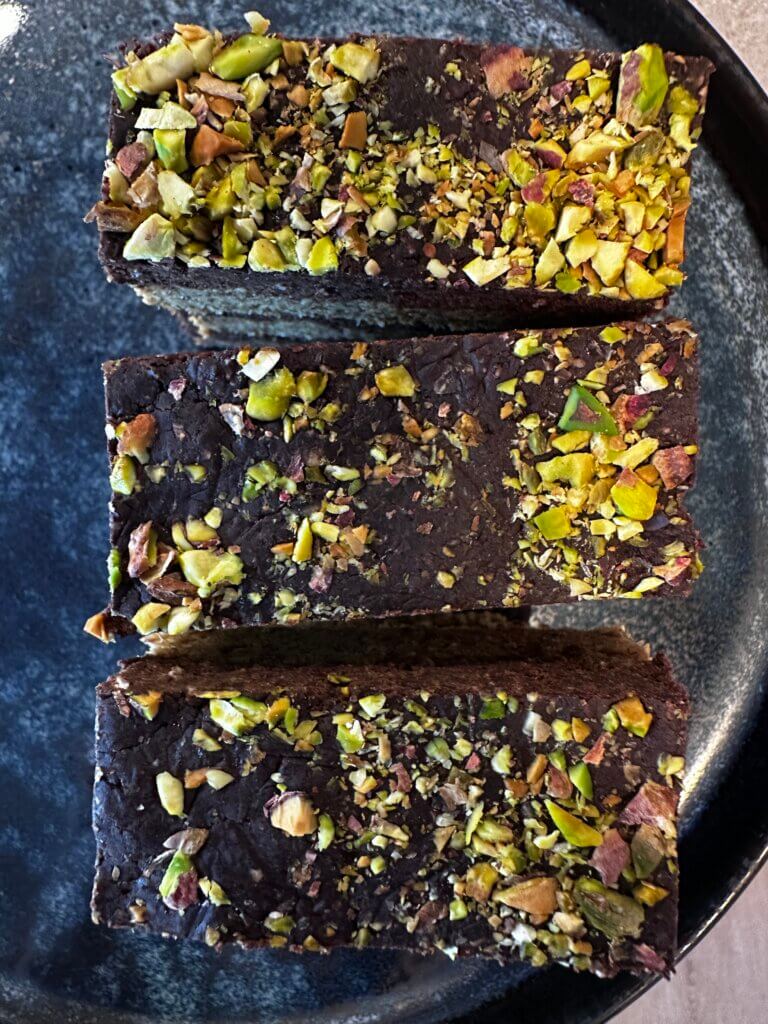 Nahaufnahme von Schoko-Nuss-Schnitten mit gehackten Pistazien – gesunder veganer Energieriegel